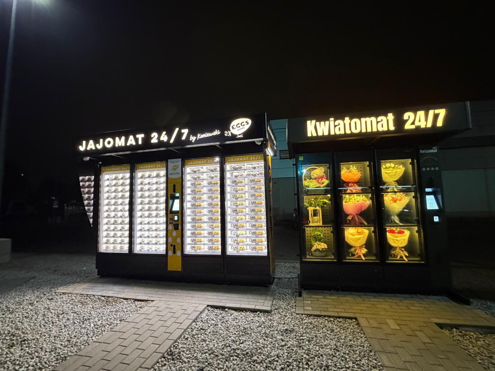 Illuminated egg and flower vending machines at night